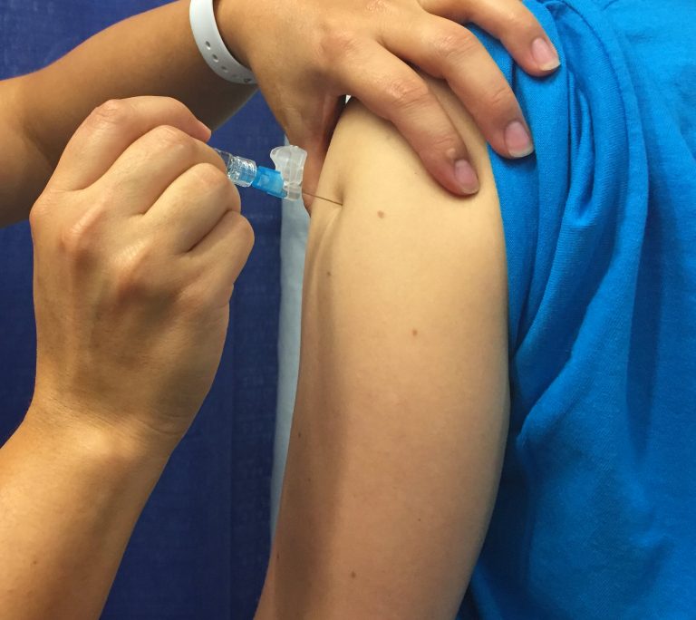 Influenza or flu vaccine being administered via a needle.